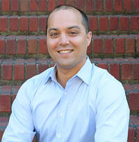 Headshot of James Olzmann, person with dark hair wearing a light blue collared shirt