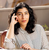 Headshot of Solmaz Sharif; person with shoulder length dark hair, wearing a white blouse 